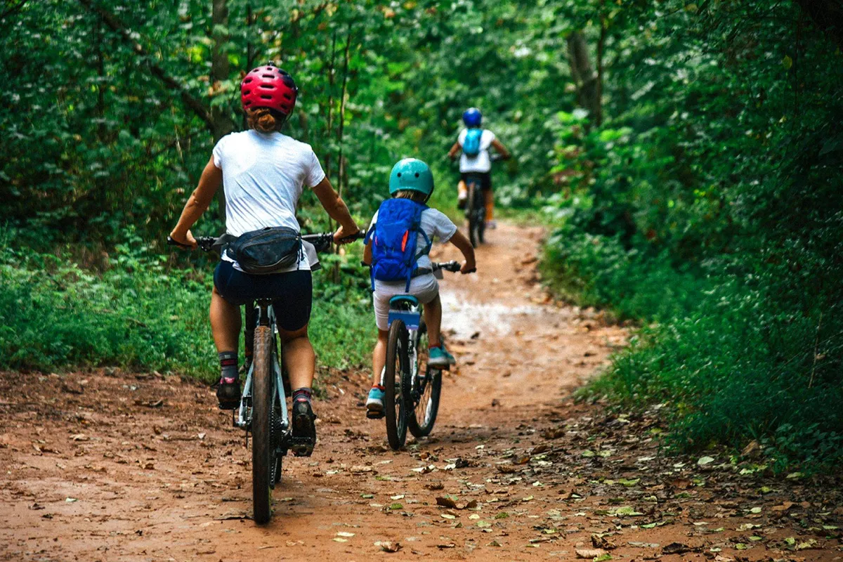 This image features cyclists on a dirt path surrounded by lush greenery, evoking an adventurous and energetic mood. The scene captures the essence of outdoor activity and communal fun, suggesting easy access to local adventures.