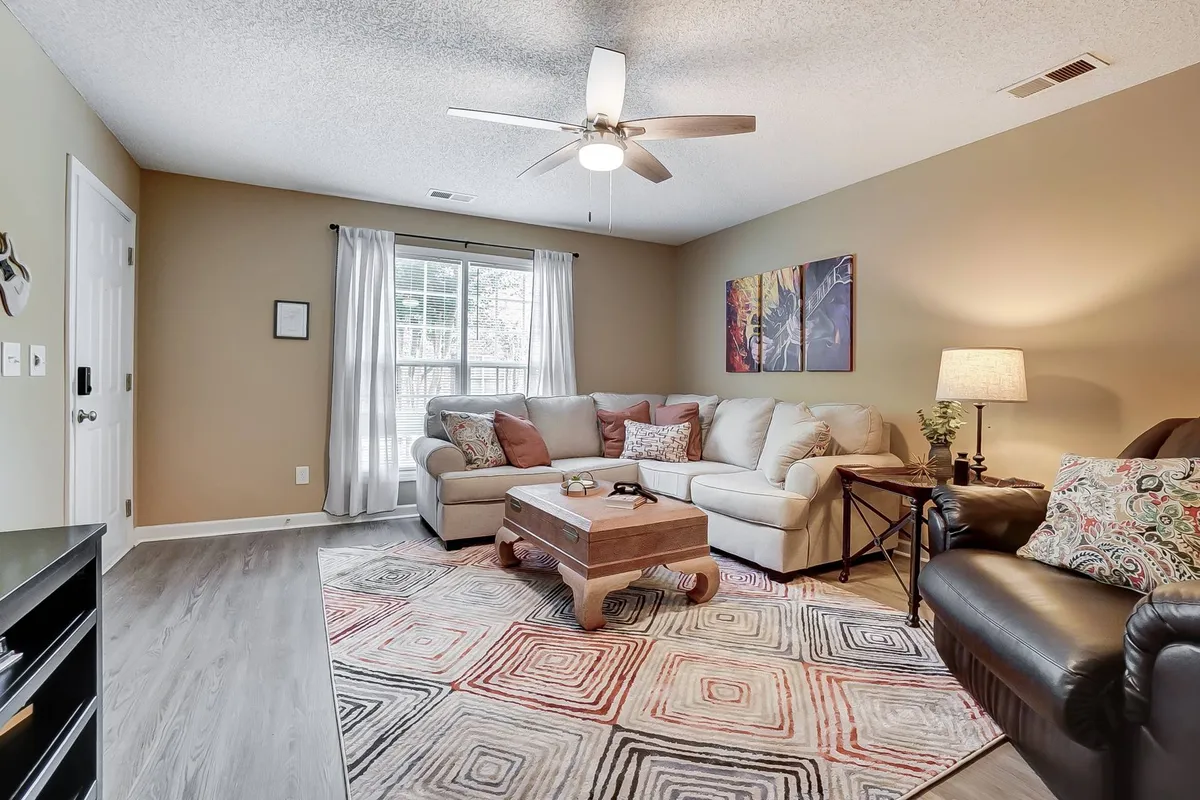 A well-appointed living room with a sofa set, coffee table, area rug, and art adorning the walls. The space exudes warmth and is ideal for intimate conversations, reading, or simply enjoying quiet moments by the window.
