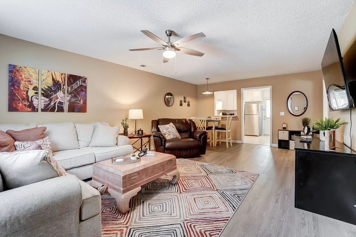 An open-concept living space that blends a sofa, coffee table, artwork, dining area, and television. The space feels inviting and designed for group interaction, whether relaxing, entertaining, or enjoying shared activities like game nights.